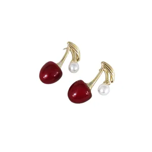 Minimalistische rote Kirschohrringe mit weißer Perle und Goldstiel auf weißem Hintergrund
