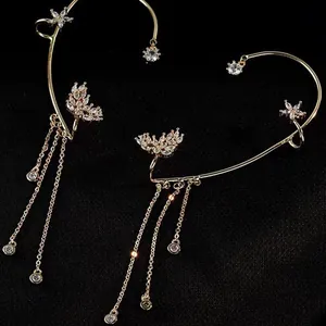 Ear cuff dorati a farfalla con nappe e cristalli scintillanti su sfondo nero raffinato