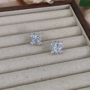 Macro detail of silver starburst ear cuff with zircon stones on a beige jewelry tray
