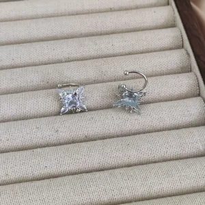 Elegant star-shaped silver ear cuff with sparkling zircon stone on a beige jewelry display