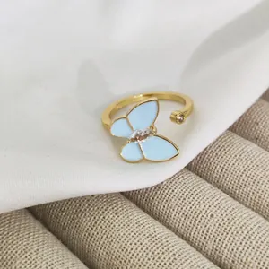 Macro shot of gold adjustable ring featuring a light blue enamel butterfly and zircon
