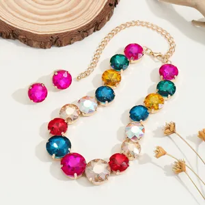 Set collana e orecchini con strass colorati e montatura dorata su sfondo beige