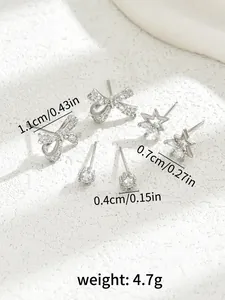 Detail shot of silver stud earrings set with zircon stars and bows on white stone