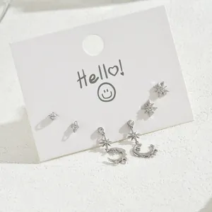 Detailed view of silver star and moon earrings set with sparkling zircon on a white card