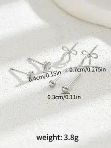 Detailed view of silver stud earring set featuring flower, bow, and bead shapes with sizes