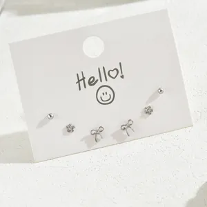 Three pairs of minimalist silver stud earrings with star, floral and bowknot designs