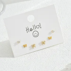 Three-pair gold bow and zircon stud earring set on a white minimalist display card