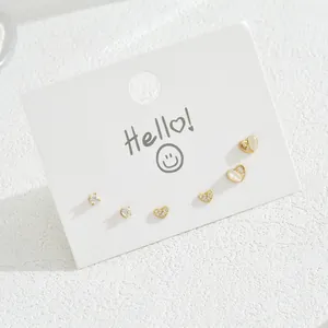 Five-piece gold stud earring set with zircons and white heart-shaped stones on card