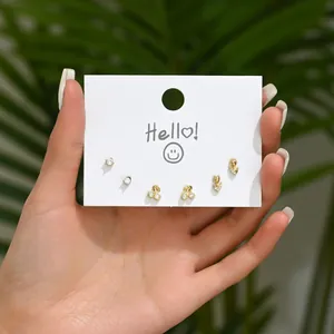Three-pair gold stud earring set with cherry and flower designs on display card