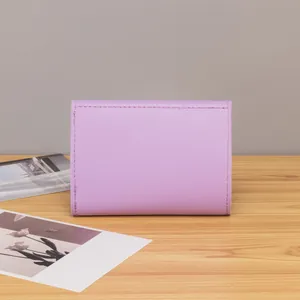 Close-up of minimalist purple leather trifold wallet with delicate stitching on wood