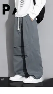 Detail of gray loose-fit cargo pants featuring side seams and a white drawstring waist