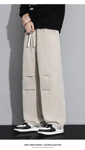 Detail of loose beige cargo pants with drawstring waist and horizontal stitching accents