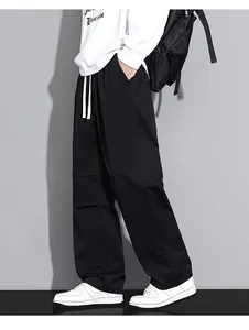 Side view of men's loose black cargo trousers with white drawstring and wide-leg fit