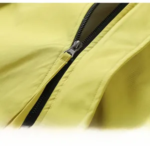 Détail de la fermeture éclair en métal noir sur une veste d'extérieur jaune coupe-vent