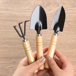 Three-piece mini gardening tool set with wooden handles and black metal heads for potting