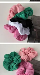 Close-up of soft colorful terry cloth scrunchies with elegant silver metal logo tags