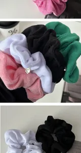 Detail of plush fabric scrunchies in pink, white, black and green with metal tags
