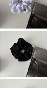 Close-up of soft terry fabric scrunchies in white and black with gold metal charms