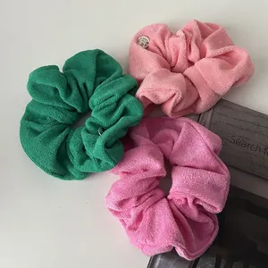 Three large plush scrunchies in green and pink toweling fabric with gold metal charms