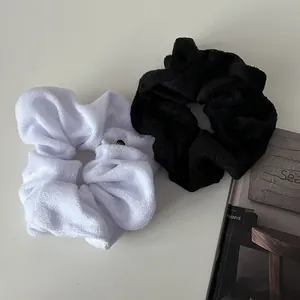Set of two plush scrunchies in black and white towel fabric with metallic accents