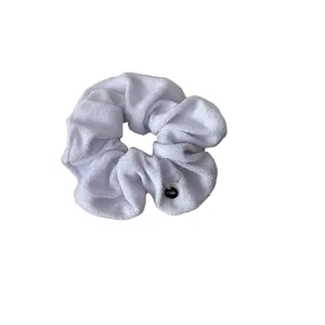 Soft white plush scrunchie with towel fabric texture and golden circular tag decoration