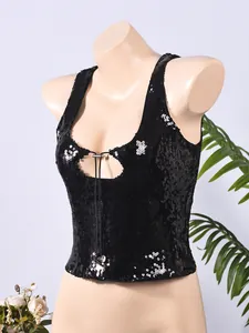 Détail d'un crop top noir à paillettes avec découpe et pendentifs en métal en cœur