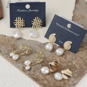 Vintage baroque pearl earrings with golden geometric designs on textured stone background