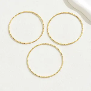 Tre bracciali rigidi sfaccettati placcati oro 18K per donna su sfondo bianco testurizzato