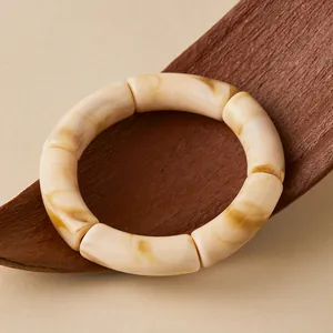 Détail de bracelet en acrylique courbé avec texture marbre beige et design rétro chic