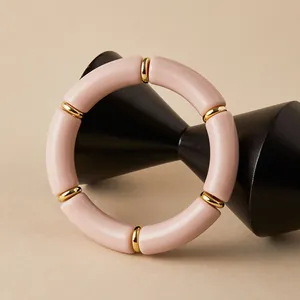 Dettaglio delle perle in acrilico rosa e distanziatori dorati su un supporto espositivo