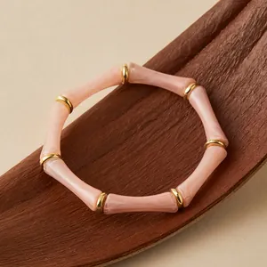 Vista detallada de las cuentas de bambú de acrílico rosa con anillos dorados y textura mármol