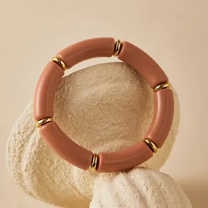 Dettaglio di perle acriliche bohémien e distanziatori dorati su un bracciale rosa