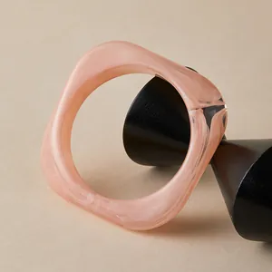 Detail view of a wide pink marble pattern acrylic resin bangle on a geometric stand