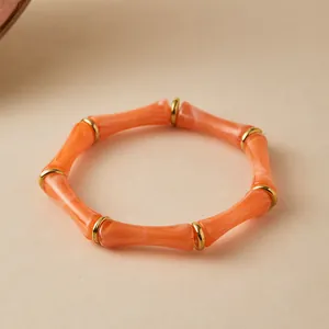 Primer plano del brazalete de resina de bambú naranja con espaciadores de metal dorado