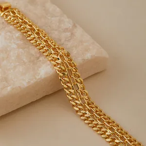 Vista de detalle de pulsera de cadena multicapa chapada en oro 18K sobre fondo mármol