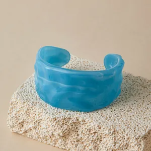 Gros plan détaillé du bracelet manchette en résine bleu clair sur pierre naturelle