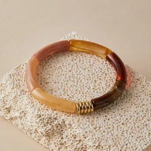 Detail of colorful resin tube bracelet with golden spiral metal accents on stone