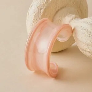 Detail view of pink acrylic cuff bracelet with marble texture on stone stand