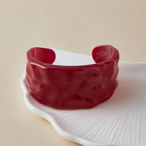 Gros plan d'un bracelet manchette en acrylique rouge translucide à texture ondulée