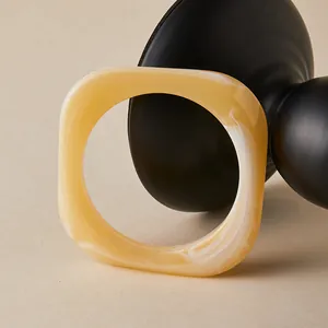 Macro detail of amber resin square bangle with white marble texture on black stand
