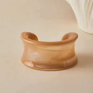 Detail of wide acrylic cuff bracelet with brown marble texture in bohemian style
