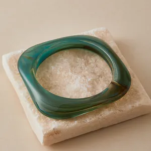 Detail of square resin bangle with dark green marble texture on a stone tray