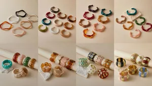 Detalle de anillos de resina ámbar y metal con texturas onduladas y mármol