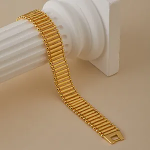 Detalle macro de pulsera multicapa chapada en oro de 18K sobre columna blanca