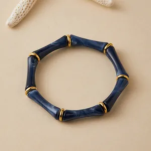 Primer plano de pulsera de acrílico azul marmoleado con diseño de bambú y aros dorados