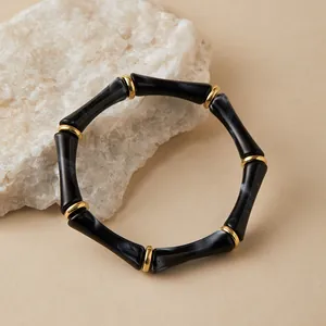 Detalle de pulsera elástica estilo bambú con cuentas de resina veteada negra y dorada