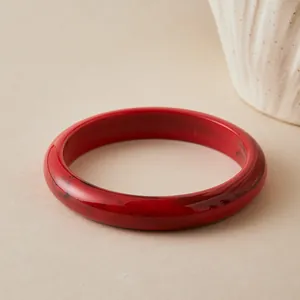 Detailed view of red marble textured acrylic bangle on a minimalist beige background
