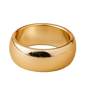 Minimalistischer dicker goldener Breitbandring mit poliertem Metallic-Finish auf weiß