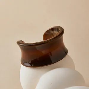 Detail of amber brown acrylic cuff bracelet with marble texture on minimalist stand