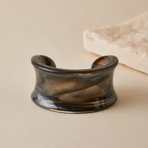 Macro view of wide acrylic open cuff bracelet featuring smoky brown marble texture